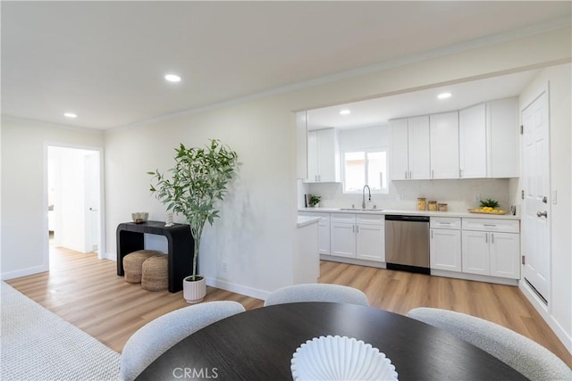 kitchen featuring sink, crown molding, light hardwood / wood-style flooring, dishwasher, and white cabinets