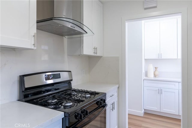 kitchen with white cabinetry, extractor fan, light wood-type flooring, and gas range oven