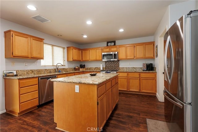 kitchen featuring dark wood-type flooring, sink, a center island, stainless steel appliances, and light stone countertops