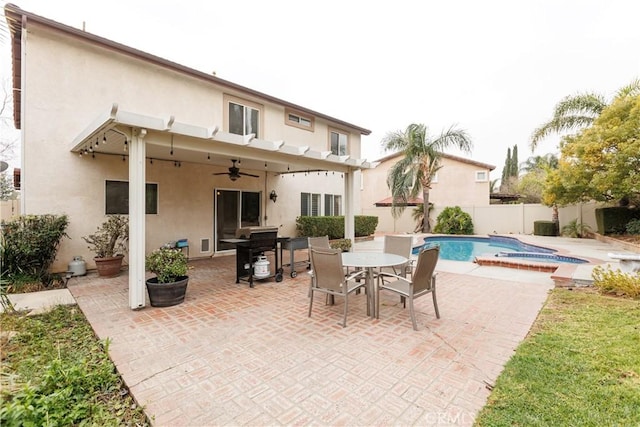 rear view of property featuring ceiling fan, a fenced in pool, and a patio