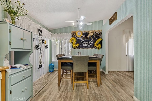 dining space featuring ceiling fan, light hardwood / wood-style flooring, a textured ceiling, and vaulted ceiling