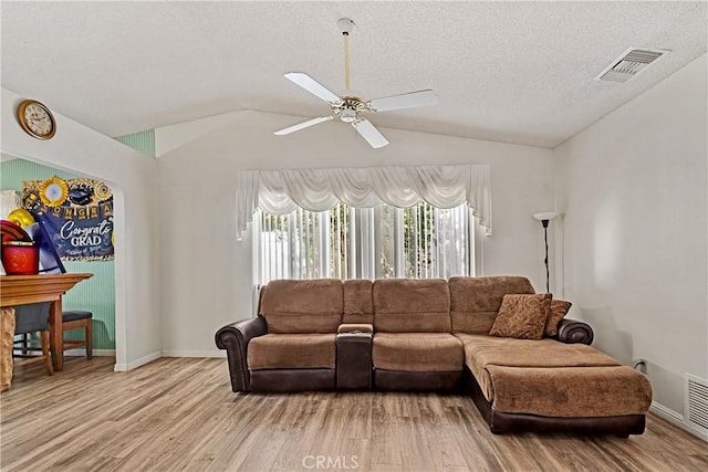 living room with lofted ceiling, a textured ceiling, and light hardwood / wood-style floors