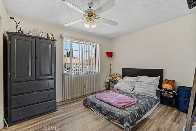 bedroom with ceiling fan, wood-type flooring, and a textured ceiling