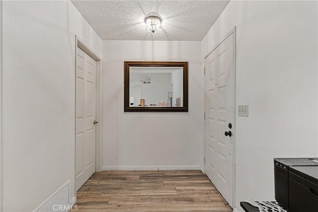 doorway to outside featuring a textured ceiling and light hardwood / wood-style flooring