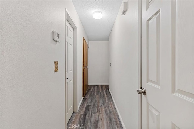 corridor with dark wood-type flooring and a textured ceiling