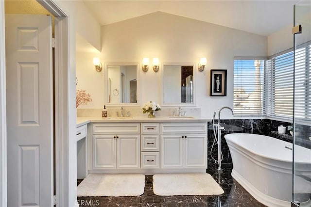 bathroom featuring vanity, a bath, and vaulted ceiling