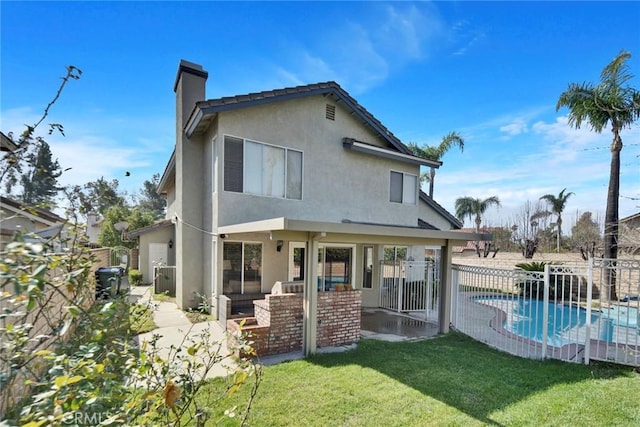 rear view of property featuring a yard, a fenced in pool, and a patio