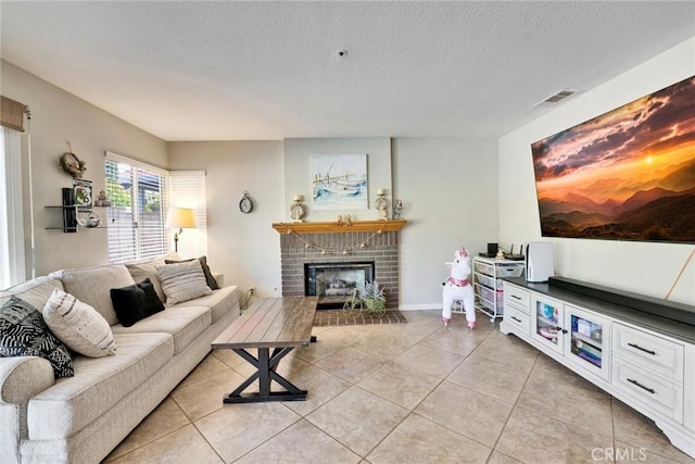 living room featuring a fireplace, a textured ceiling, and light tile patterned floors