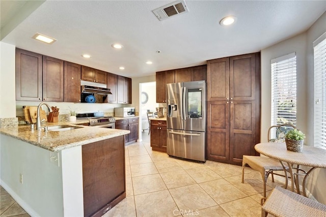 kitchen featuring sink, light tile patterned floors, kitchen peninsula, stainless steel appliances, and light stone countertops