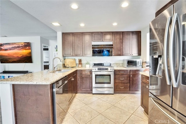 kitchen featuring stainless steel appliances, kitchen peninsula, sink, and light stone countertops