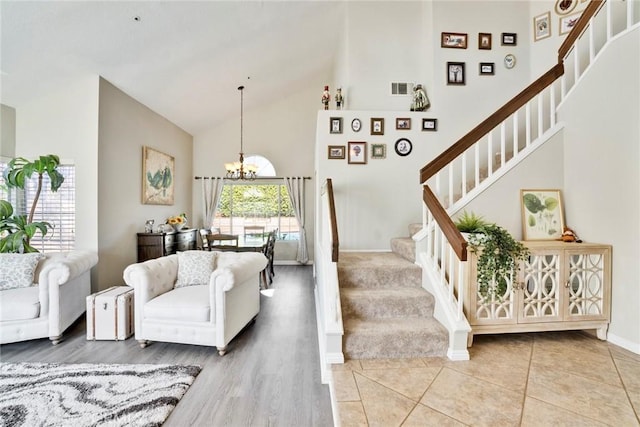 living room with an inviting chandelier, tile patterned floors, and high vaulted ceiling