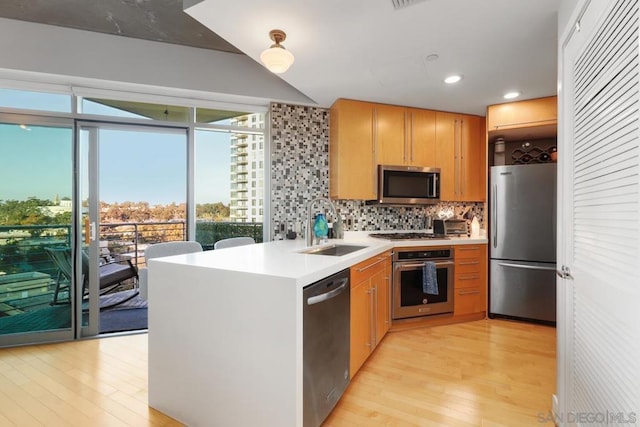 kitchen featuring stainless steel appliances, sink, backsplash, and light hardwood / wood-style floors