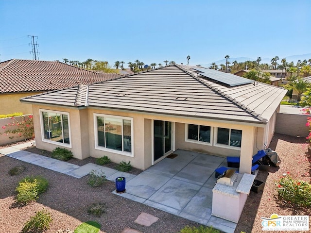 rear view of property with solar panels and a patio area