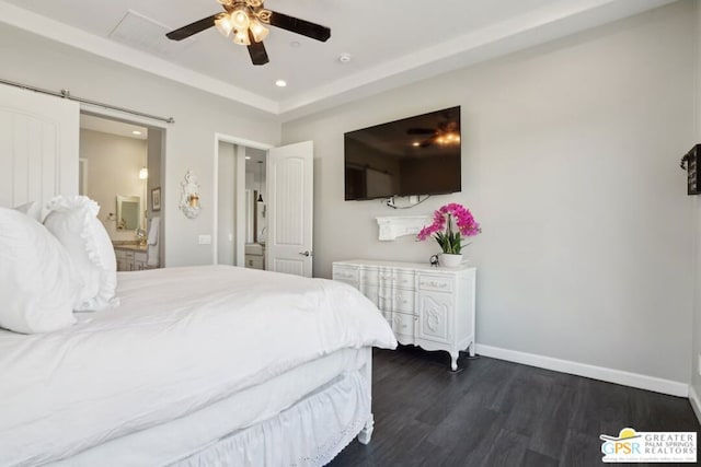 bedroom with a tray ceiling, dark hardwood / wood-style floors, a barn door, and ceiling fan