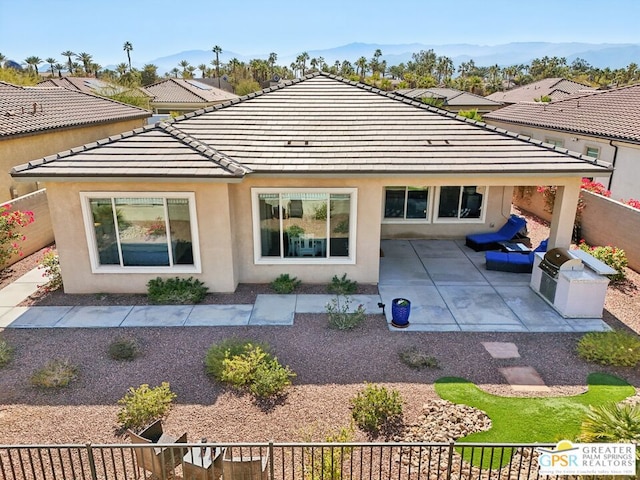 back of property featuring exterior kitchen, a patio, and a mountain view