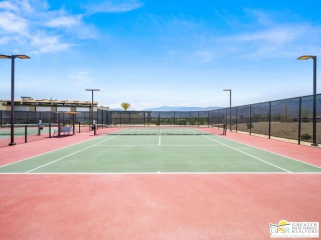 view of tennis court with a mountain view and basketball hoop