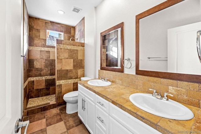 bathroom with tasteful backsplash, vanity, toilet, and tiled shower