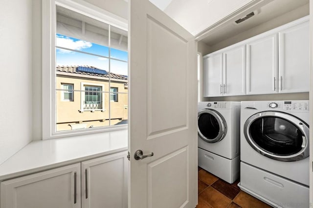 laundry area with cabinets, separate washer and dryer, and dark tile patterned flooring