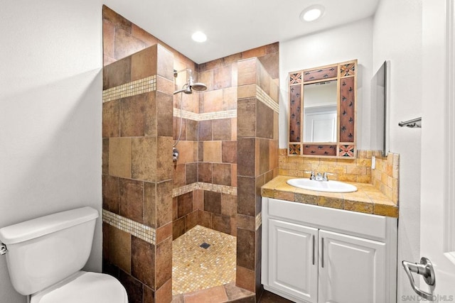 bathroom with tiled shower, vanity, toilet, and backsplash