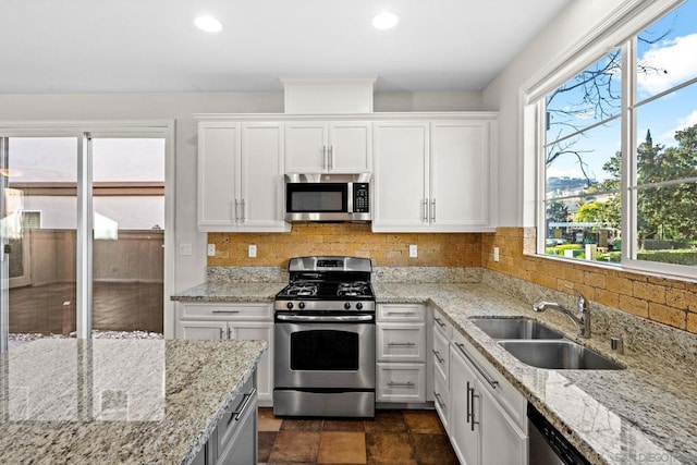 kitchen featuring sink, white cabinetry, tasteful backsplash, light stone counters, and stainless steel appliances