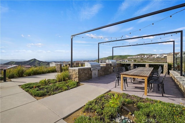 view of home's community featuring an outdoor kitchen, a mountain view, and a patio area