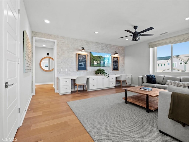 living room with ceiling fan, built in desk, and light wood-type flooring