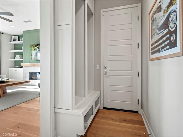 mudroom featuring ceiling fan, a fireplace, and light hardwood / wood-style floors