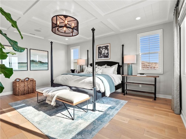 bedroom with beamed ceiling, coffered ceiling, light hardwood / wood-style floors, and a notable chandelier