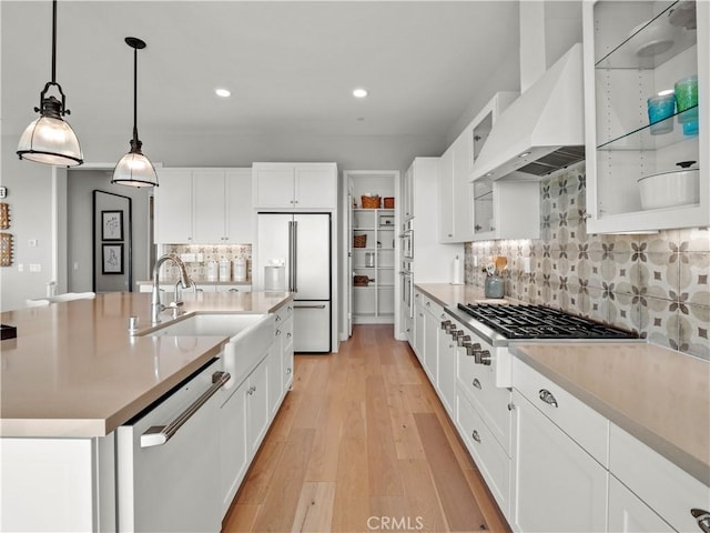 kitchen featuring wall chimney exhaust hood, dishwashing machine, an island with sink, high end white fridge, and white cabinets