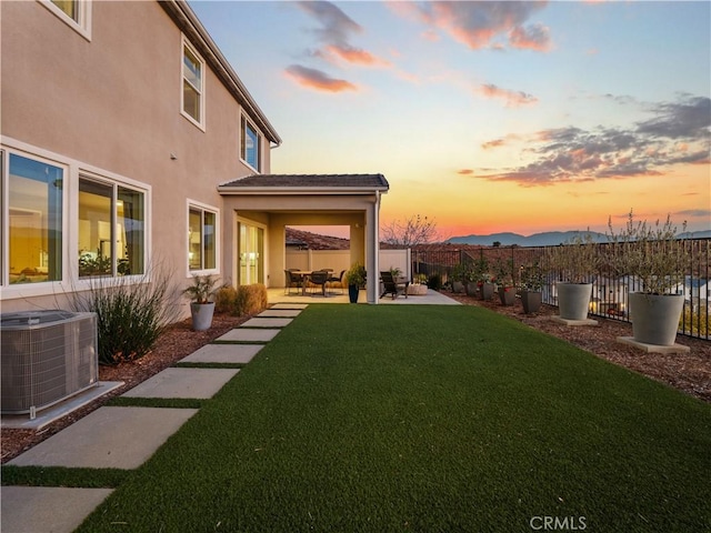 yard at dusk featuring a patio area and central air condition unit