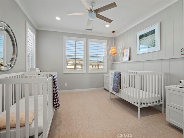 carpeted bedroom with ceiling fan, ornamental molding, and a crib