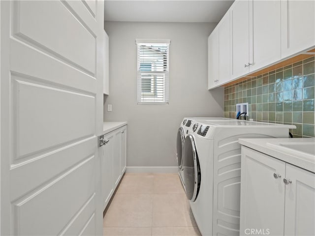 laundry room featuring washer and dryer, light tile patterned floors, and cabinets