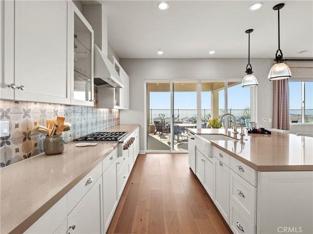 kitchen with hanging light fixtures, white cabinetry, sink, and decorative backsplash