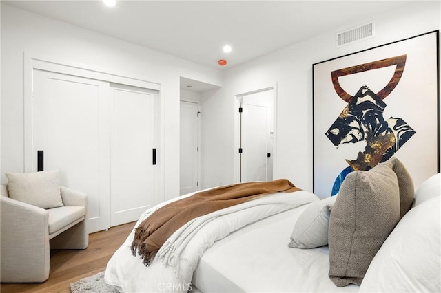 bedroom with light hardwood / wood-style floors and a closet