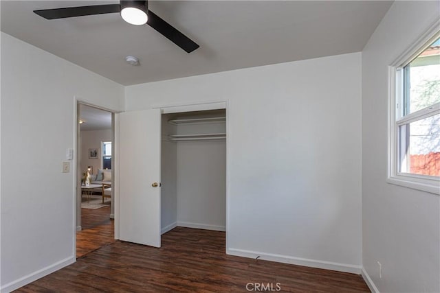 unfurnished bedroom with ceiling fan, dark hardwood / wood-style flooring, and a closet