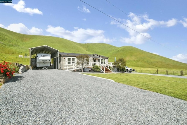 view of front of home with a carport, a mountain view, a rural view, and a front lawn