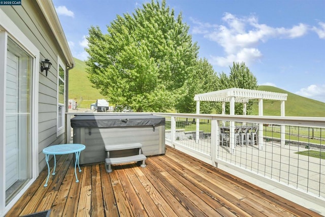 wooden deck featuring a hot tub and a pergola