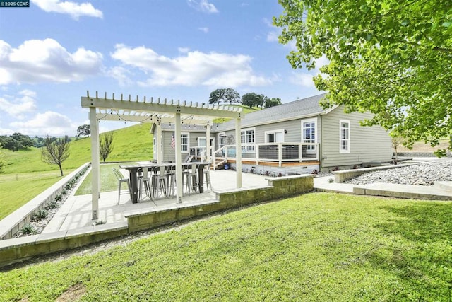 rear view of property with a wooden deck, a pergola, a lawn, and a patio area