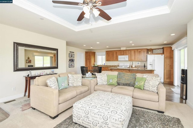 living room with ornamental molding, sink, and a tray ceiling