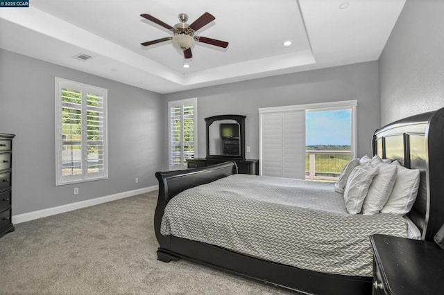 carpeted bedroom featuring a raised ceiling and ceiling fan