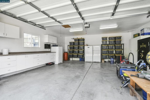 garage featuring white refrigerator and a garage door opener