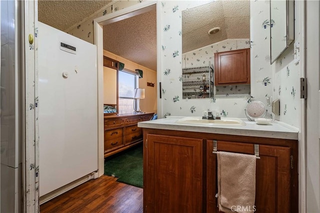 bathroom featuring vanity, hardwood / wood-style flooring, vaulted ceiling, and a textured ceiling