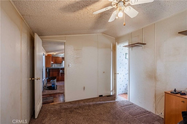 carpeted spare room featuring lofted ceiling, ceiling fan, and a textured ceiling