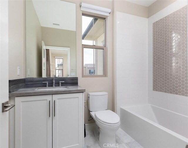 full bathroom with tiled shower / bath, vanity, and toilet