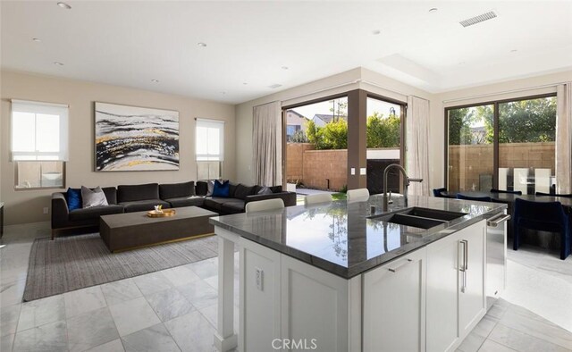 kitchen featuring dark stone countertops, sink, a wealth of natural light, and white cabinets