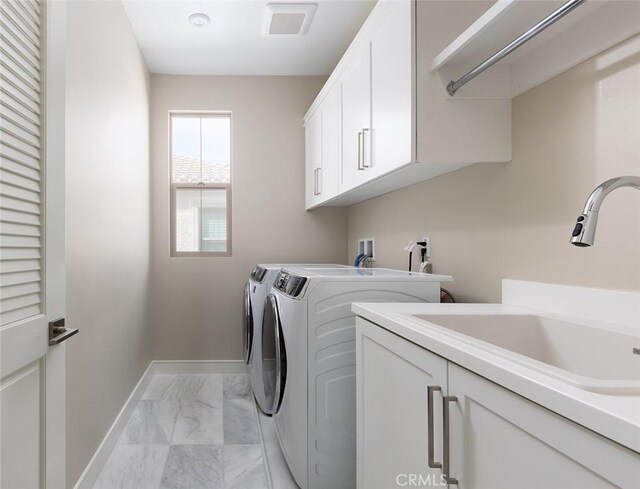 laundry area with cabinets, washing machine and dryer, and sink