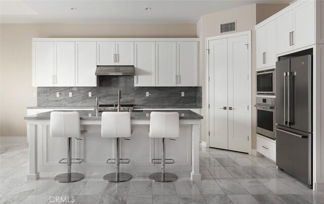 kitchen featuring white cabinetry, appliances with stainless steel finishes, and a kitchen breakfast bar