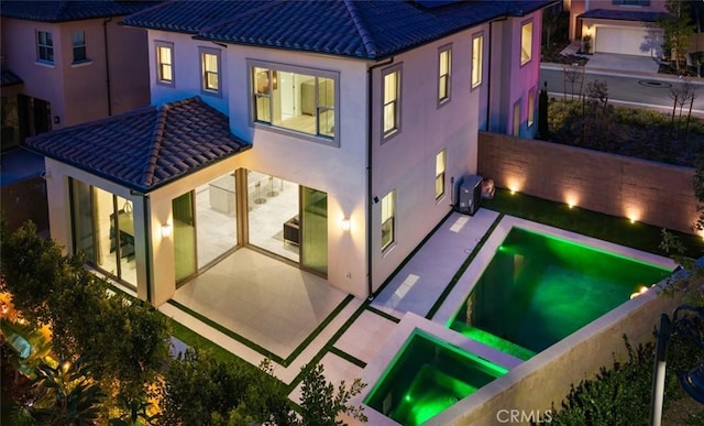 rear view of property featuring an in ground hot tub and a patio area