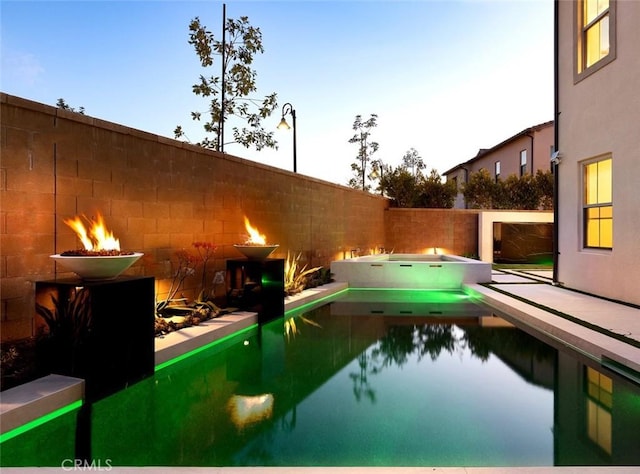 pool at dusk with an in ground hot tub