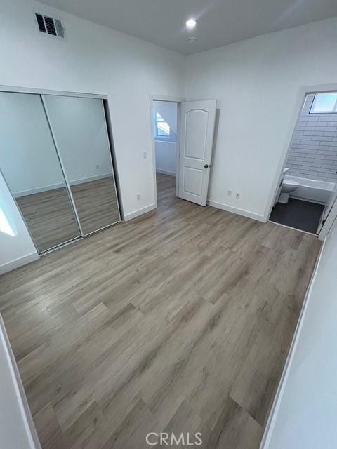 unfurnished bedroom featuring multiple windows and light wood-type flooring